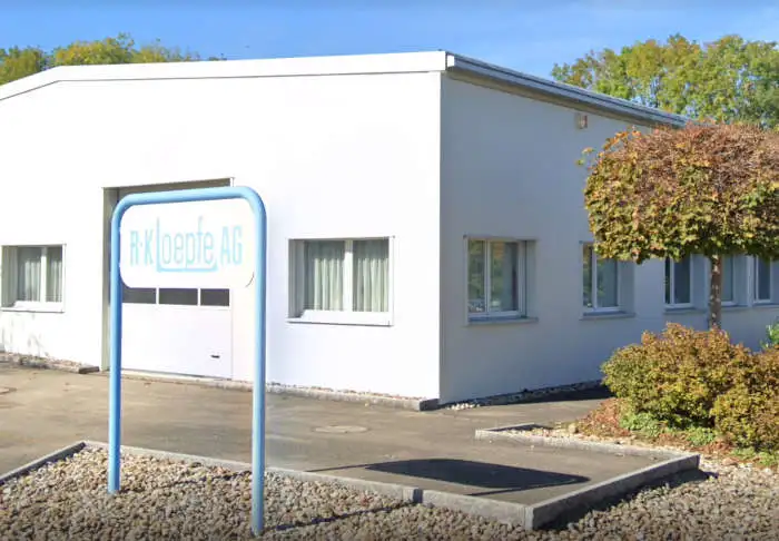 The company building with a sign in front of it with the logo of R+K Loepfe AG